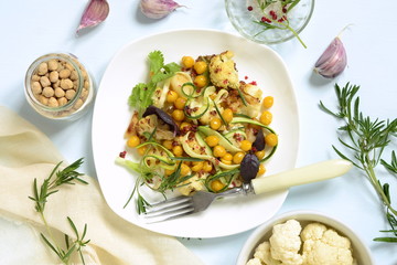 Roasted cauliflower with chickpeas, zucchini noodles and rosemary, salad, top view
