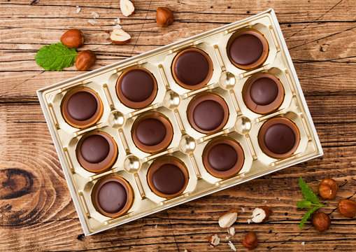 Box of homemade candies on wooden background with mint and nuts. A hazelnut in Caramel and chocolate.