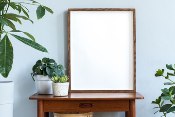 Stylish scandinavian interior with design retro table, brown mock up photo frame and beautiful...