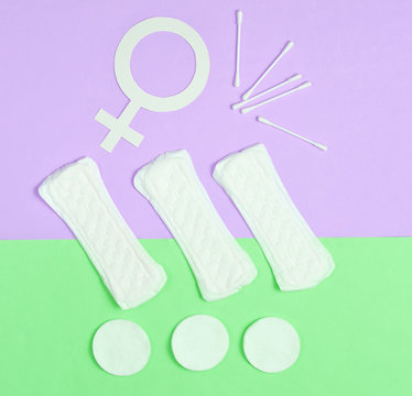 Products for feminine hygiene, self-care and health, female gender symbol on pastel background. Ear sticks, pads. Top view