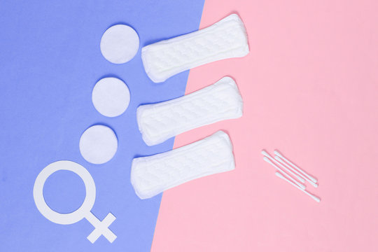 Products for feminine hygiene, self-care and health, female gender symbol on pastel background. Ear sticks, pads. Top view