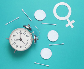 Self care time. Products for hygiene, female gender symbol, retro alarm clock on blue  background. Top view. Flat lay