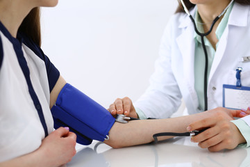 Unknown doctor woman checking blood pressure of female patient, close-up. Cardiology in medicine  and health care concept