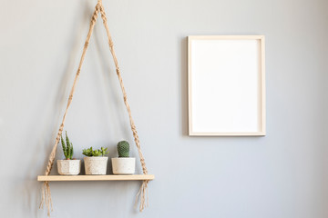 Stylish and minimalistic scandinavian interior with mock up poster frame and hanging wooden shelf...