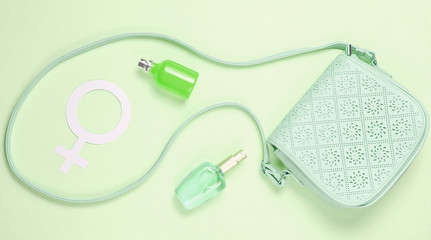 Leather bag, gender symbol of women, perfume bottles on pastel green background. Duotone effect. Top view