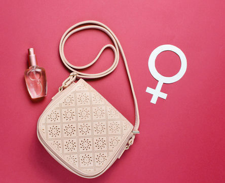 Women's fashion bag, perfume bottle, gender feminism symbol on red background. Top view. Minimalism