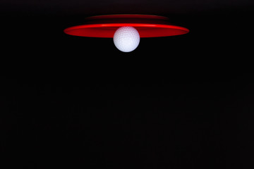 Red decorative lamp with light bulb as a golf ball. Photo of a red plate and golf ball.