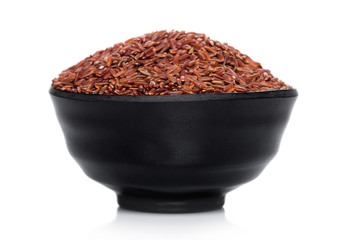 Black bowl of raw organic red rice on white background. Healthy food.