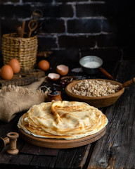 Homemade stack of crepes on wooden plate stand on rustic table with plate of ground fried beef