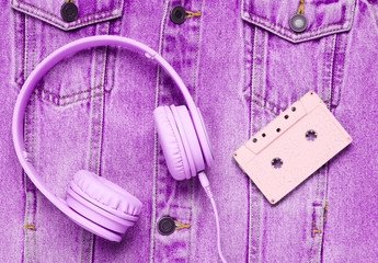 Pop culture attributes eighties. Headphones, audio cassette on denim background. Top view