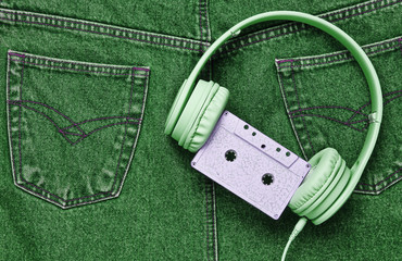 Retro style, 80s. Headphones, audio cassette on back pocket of green jeans. Pop culture. Minimalism. Top view