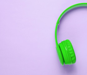 Half of mint green headphones on a purple pastel background. Top view. Copy space