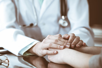 Doctor and  female patient sitting at the desk and talking  in clinic near window. Medicine and health care concept. Green is main color