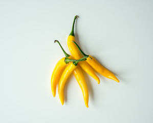 Żółte papryczki chili leżące na białym tle. Ostry dodatek do potrawy.  - obrazy, fototapety, plakaty