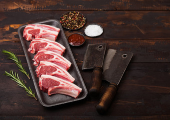 Fresh raw butchers lamb beef cutlets in plastic tray with vintage meat hatchets on wooden background.Salt, pepper and oil in steel bowl. © DenisMArt