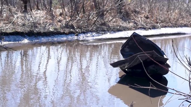 he inner part of the wing of the car in a puddle of water in the absence of asp The torn off wing of an old black car floats in a puddle on a bad road in bright daylight 