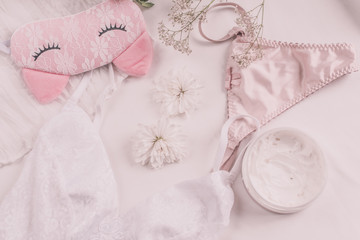 Flat lay for fashion blog and social media. Woman's glamour white and beige beauty accessories on a white background. Lingerie, jewelry, perfumes, cream, soap, panties, sleep mask, spiral hair ties. 