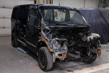 The black car in the body of the van is preparing for painting the body with the help of leveling in the places of damage to the exterior elements with rust without engine in a workshop for repair
