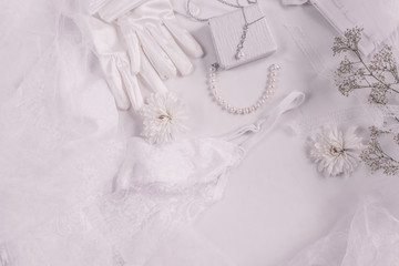 Fototapeta na wymiar White bridal accessories for wedding background with pearls, white satin ribbons and lace, gloves, bracelet,flat lay for fashion blog, top view
