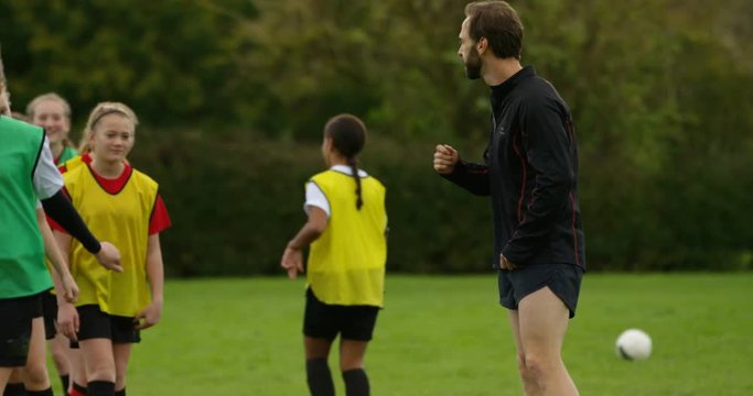 4K Cheerful coach shouting & motivating young female soccer players in training. Slow motion.