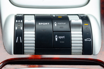 Close-up on the suspension control buttons for different road conditions with Sport level in car in the back of a suv after cleaning and detailing in the vehicle repair workshop. Auto service industry