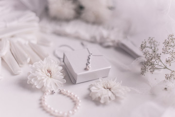 White bridal accessories for wedding background with pearls, white satin ribbons and lace, gloves, bracelet,flat lay for fashion blog, top view