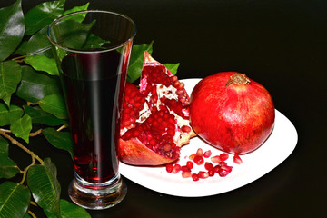 pomegranate still life on a white plate and a glass of juice