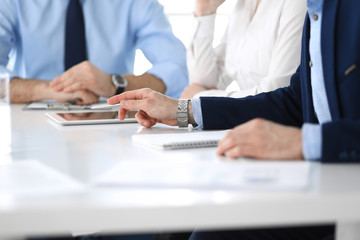 Group of unknown business people discussing questions at meeting in modern office, close-up of hands. Managers at negotiation or brainstorm. Teamwork, partnership and business concept