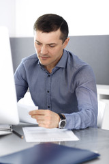 Businessman working with computer in modern office. Headshot of male entrepreneur or company director at workplace. Business concept