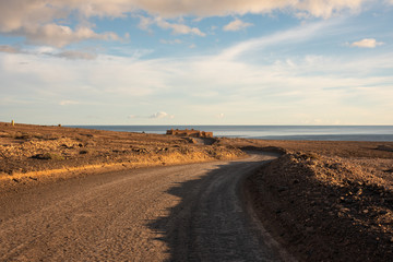 Fototapeta na wymiar Dusty road to Cofete beach during sunset. Fuerteventura, Canary Islands, Spain. 