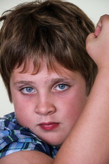 Vertical close up of cute preteen blue-eyed angry-looking boy raising his fist