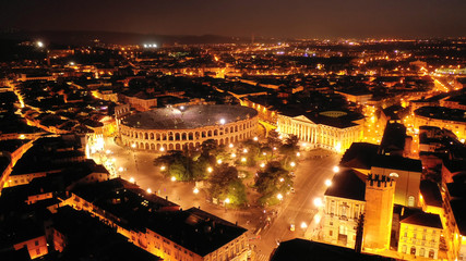 Aerial drone night shot from iconic illuminated Arena theatre and City Hall in Bra square of beautiful city of Verona, Lombardy, Italy