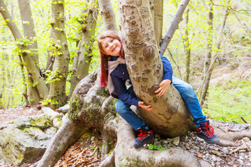 little girl sitting astride a log in a forest