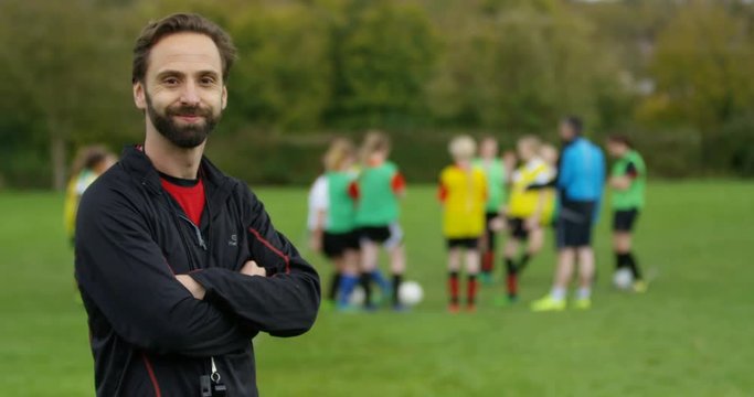 4K Portrait smiling coach at soccer training. Slow motion.
