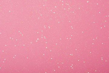 Obraz premium Golden glitter scattered on the pink card background, top view, selective focus