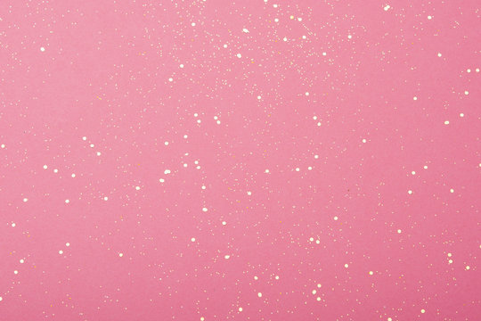 Golden glitter scattered on the pink card background, top view, selective focus