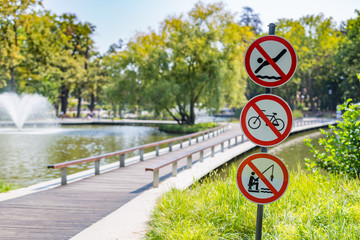 Public park warning signs, no swimming, no cycling, no fishing. red white warning signs