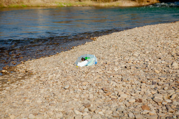 Fototapeta na wymiar River pollution near the shore, garbage near the river, plastic food waste, contributing to pollution