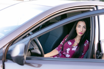 Fototapeta na wymiar Happy young asian woman driving a car with her dogs. Attractive girl driver sitting in automobile and looking through the window in summer sunset. Travel road trip with pets. Outdoor and friendship.