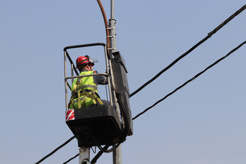 Electrician repairs the street light. Worker on the lifting platform near the lantern against the blue sky, concept of street lighting repair, power outages