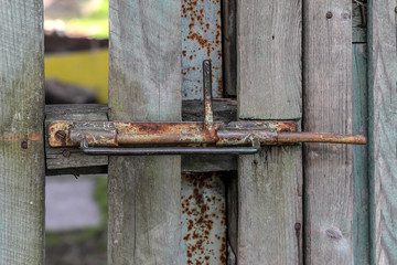 Old rusty safety lock on wooden gate in the garden