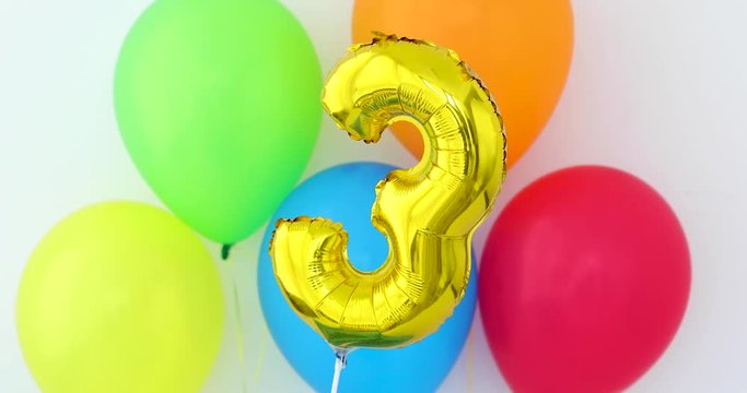 Gold foil number 3 celebration balloon on a color background