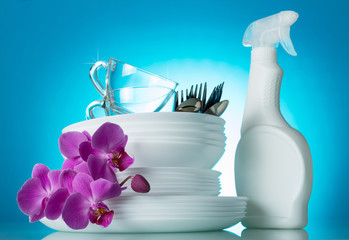 Obraz na płótnie Canvas Clean the dinner dishes are stacked, the tool from dirt, orchid flower on bright blue