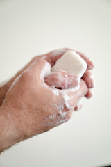 close up of man washing his hands with a bar of soap and soapy suds