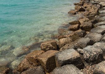sea rocky coast with clear water and dry , wet rocks on a deserted beach