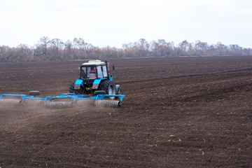 Obraz premium Farmer in tractor preparing land with seedbed cultivator