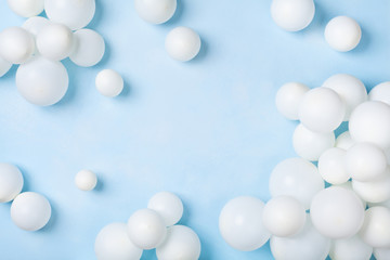 Pastel blue table with white balloons top view. Party or birthday background. Flat lay style.
