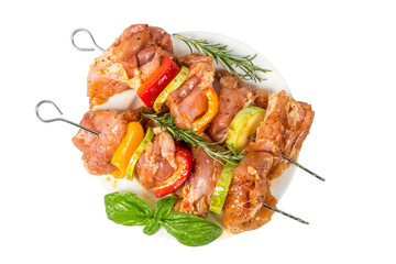 skewers of raw meat and vegetables in marinade on the plate isolated on white background. top view