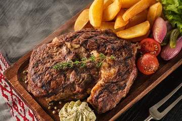 Ribeye steak with potatoes, onions and baked cherry tomatoes. Juicy steak with flavored butter
