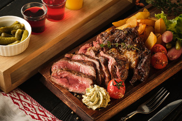 Juicy steak with fragrant butter. Sliced Ribeye Steak with Potatoes, Onions and Baked Cherry Tomatoes